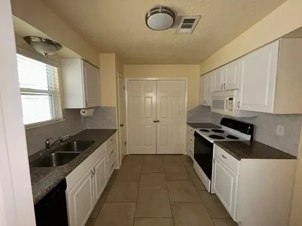 a kitchen with granite countertop a stove a sink and a refrigerator