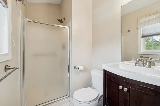 a bathroom with a sink a toilet a mirror and shower