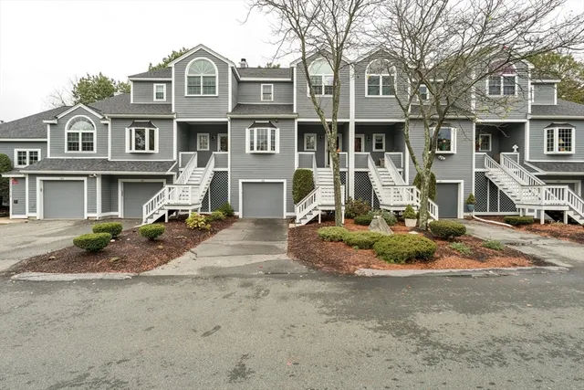 a view of a white house with large windows next to a road