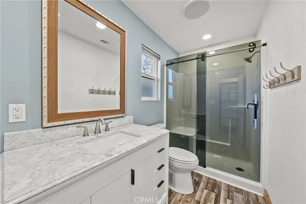 a bathroom with a granite countertop sink toilet and painting on the wall