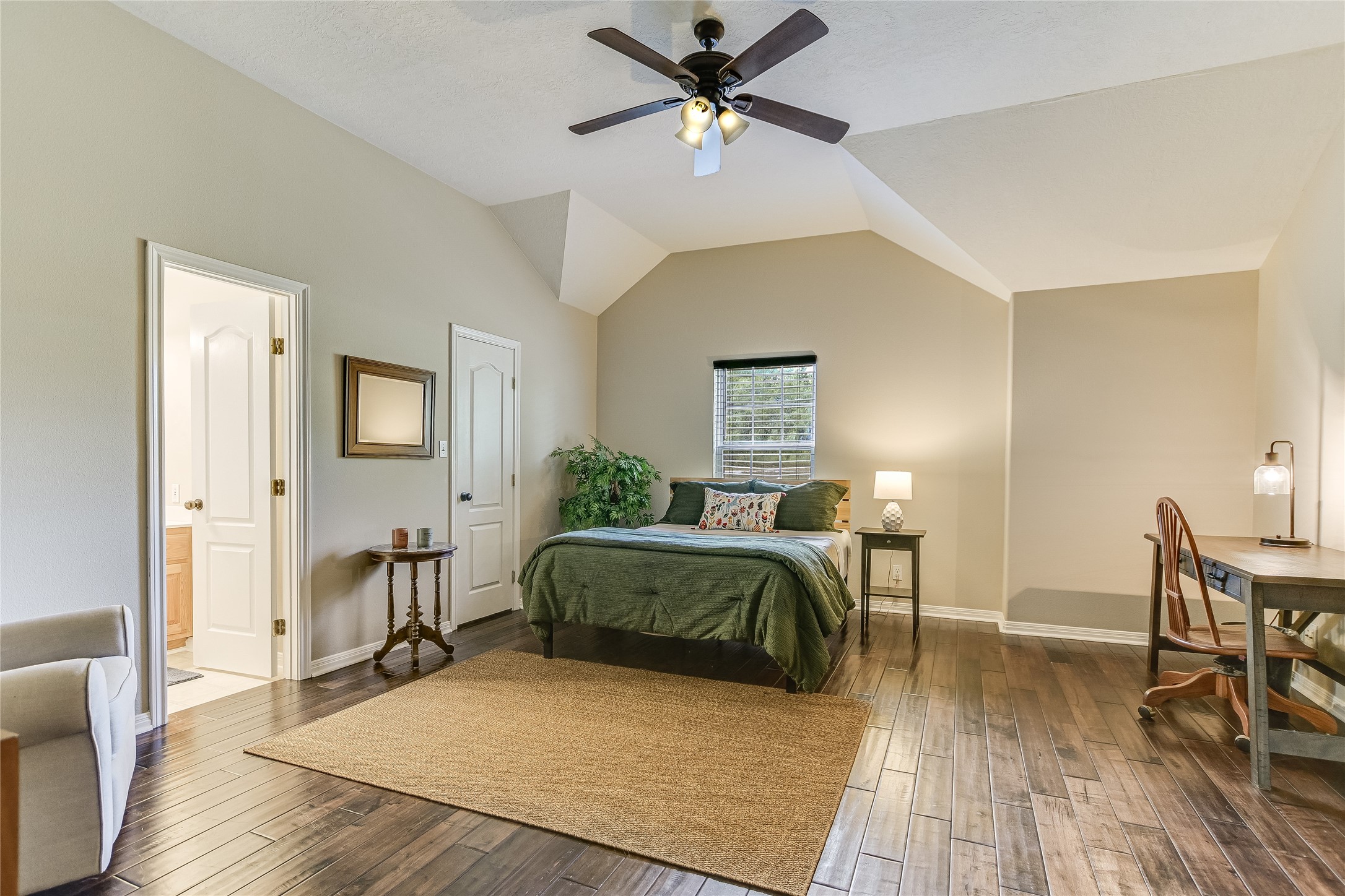 741 Knobbs Road McDade, TX 78650 - Photo 18 of 38 A comfortable bedroom with vaulted ceilings, featuring wood flooring and a refreshing ceiling fan.