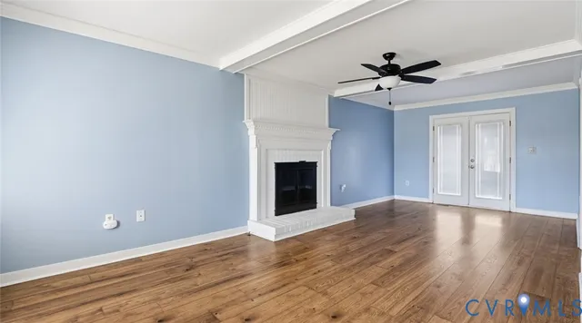 a view of an empty room with wooden floor and a ceiling fan