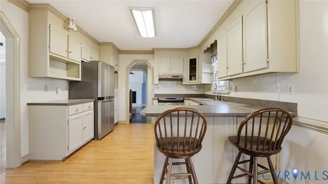 a kitchen with stainless steel appliances granite countertop a table chairs sink refrigerator and cabinets