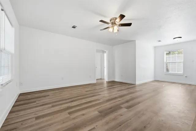 a view of empty room with wooden floor and fan