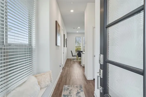 a view of a hallway with wooden floor and a bathroom