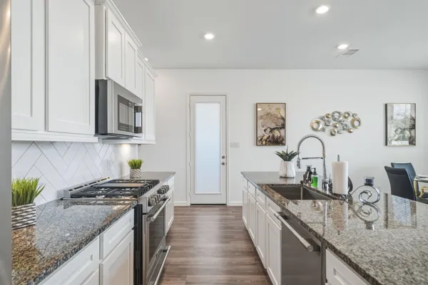 a kitchen with granite countertop stainless steel appliances sink stove and cabinets
