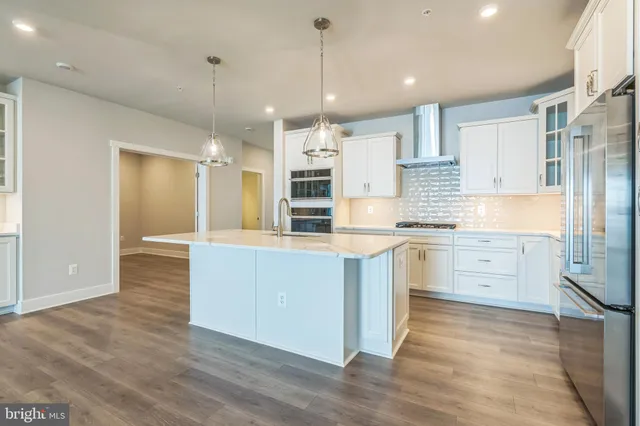 a large kitchen with white cabinets stainless steel appliances and wooden floor
