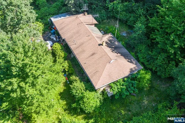 an aerial view of a house with a yard and trees all around
