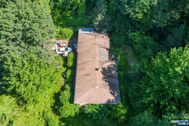 an aerial view of a house with a yard and trees all around