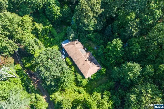 an aerial view of residential house with outdoor space and trees all around