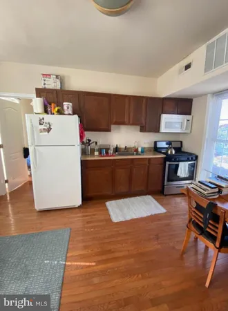 a large white kitchen with wooden floors and stainless steel appliances