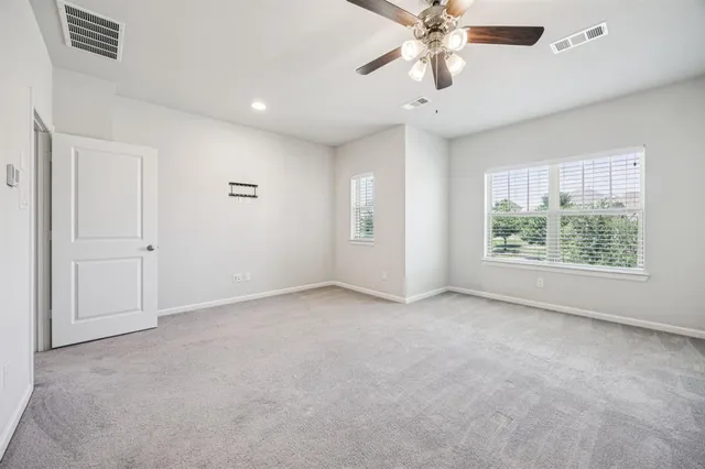 en empty room with windows and ceiling fan