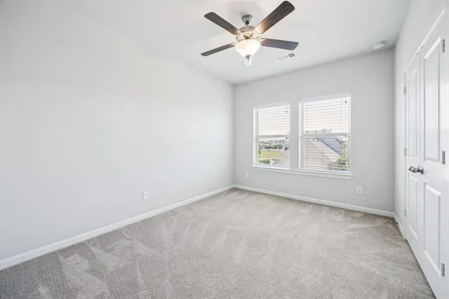 an empty room with windows and ceiling fan