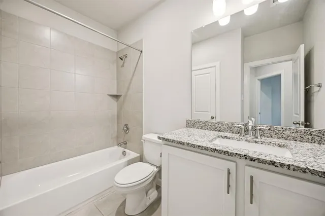 a bathroom with a granite countertop sink toilet mirror and bathtub