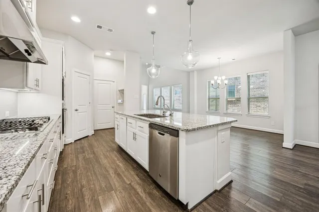 a large white kitchen with a stove a sink dishwasher and a refrigerator with wooden floor