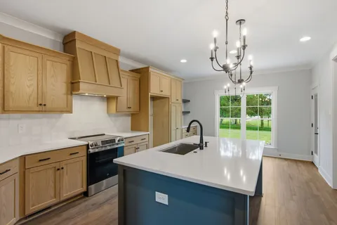 a kitchen with stainless steel appliances a sink a stove a refrigerator cabinets and wooden floor