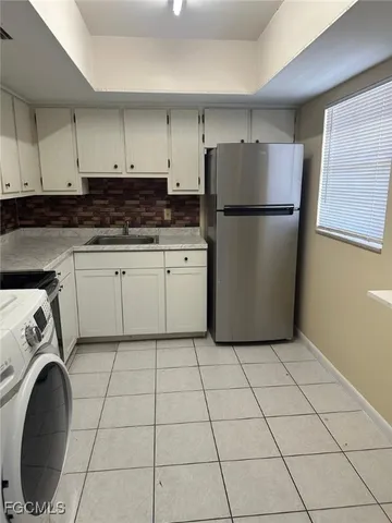 a kitchen with a refrigerator a stove top oven and cabinets