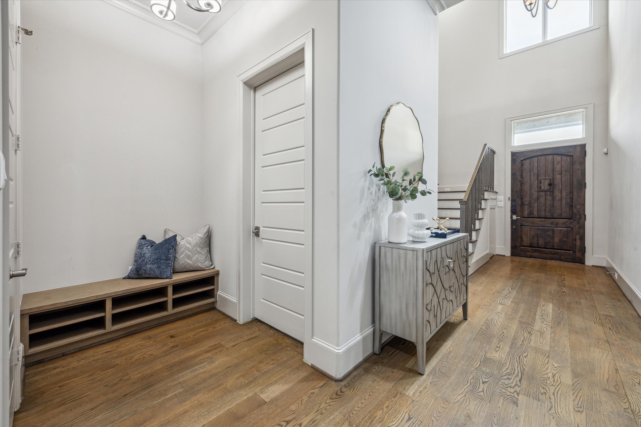4615 Verone Street Bellaire, TX 77401 - Photo 3 of 43 Step through the striking solid wood door into a grand entrance that exudes warmth and sophistication. The wide hallway, adorned with rich wood floors, sets the tone for the home's timeless elegance.