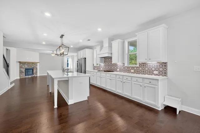 a view of an empty room with wooden floor fireplace and a window
