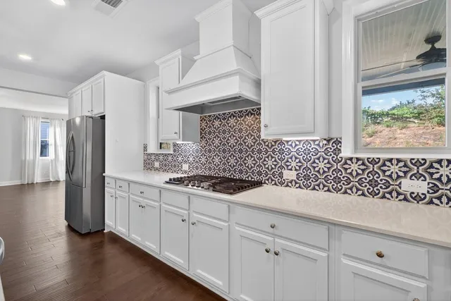 a view of an empty room with wooden floor and a fireplace