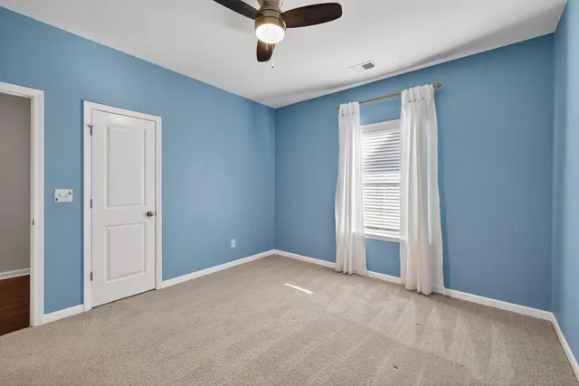 an empty room with a ceiling fan and window
