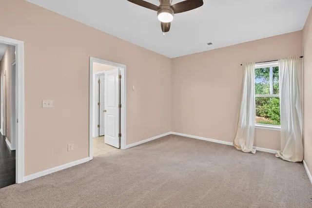 a view of a livingroom with a ceiling fan & windows