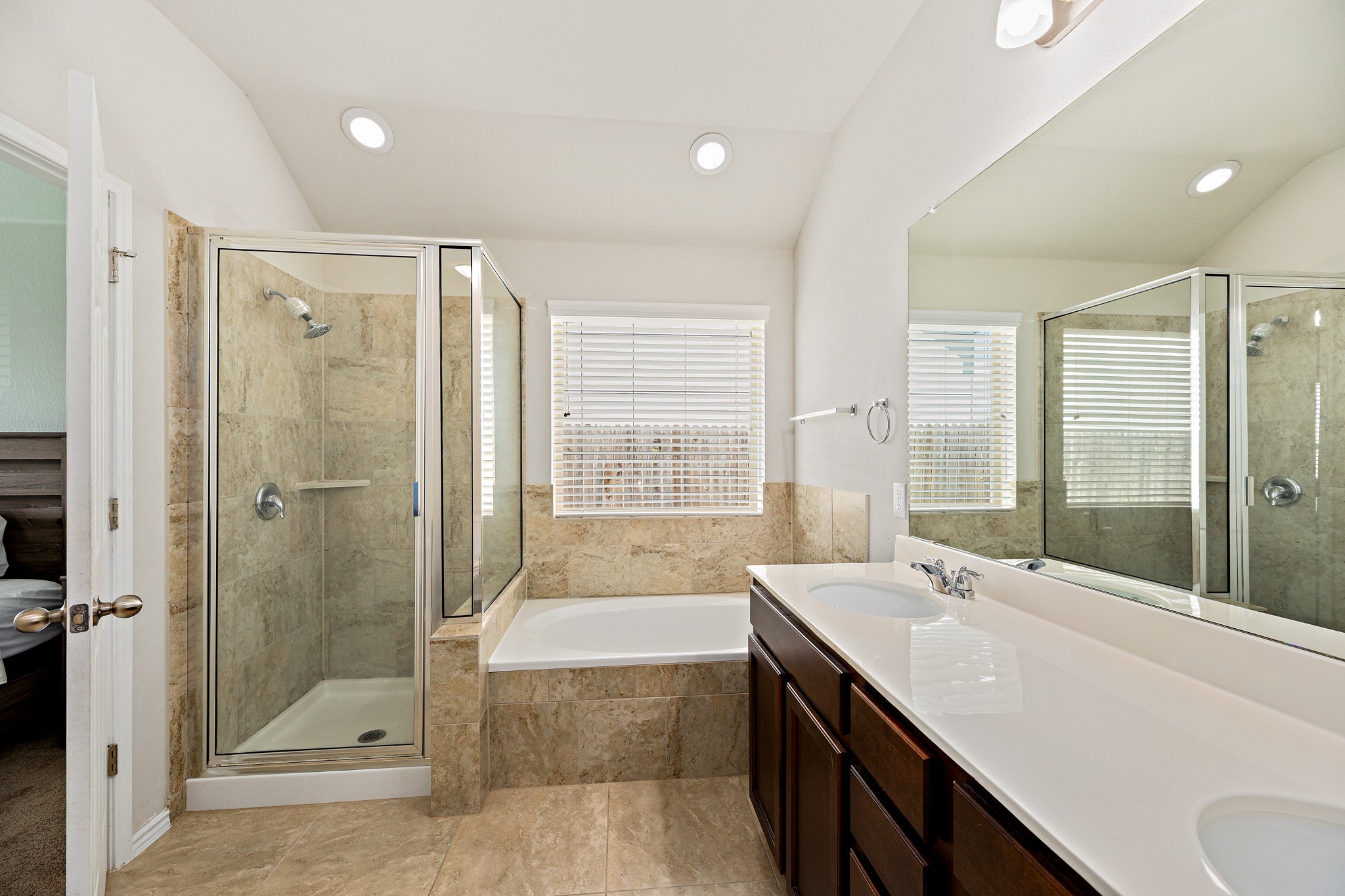 382 Limerick Road Buda, TX 78610 - Photo 13 of 20 A pristine bathroom featuring a double vanity, a glass-enclosed shower, and a relaxing soaking tub.