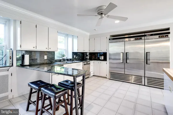a large white kitchen with stainless steel appliances kitchen island granite countertop a stove and a sink