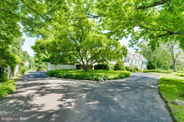 a view of a house with a big yard plants and large trees