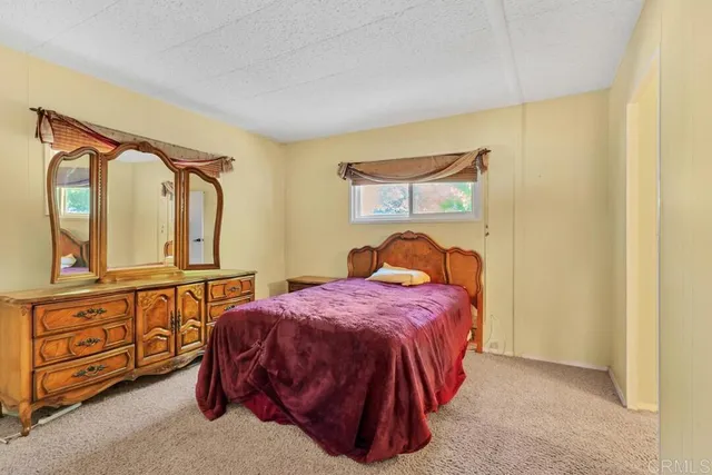 a bedroom with a bed a mirror on dresser and a window