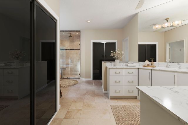 a bathroom with a granite countertop bathtub shower and mirror