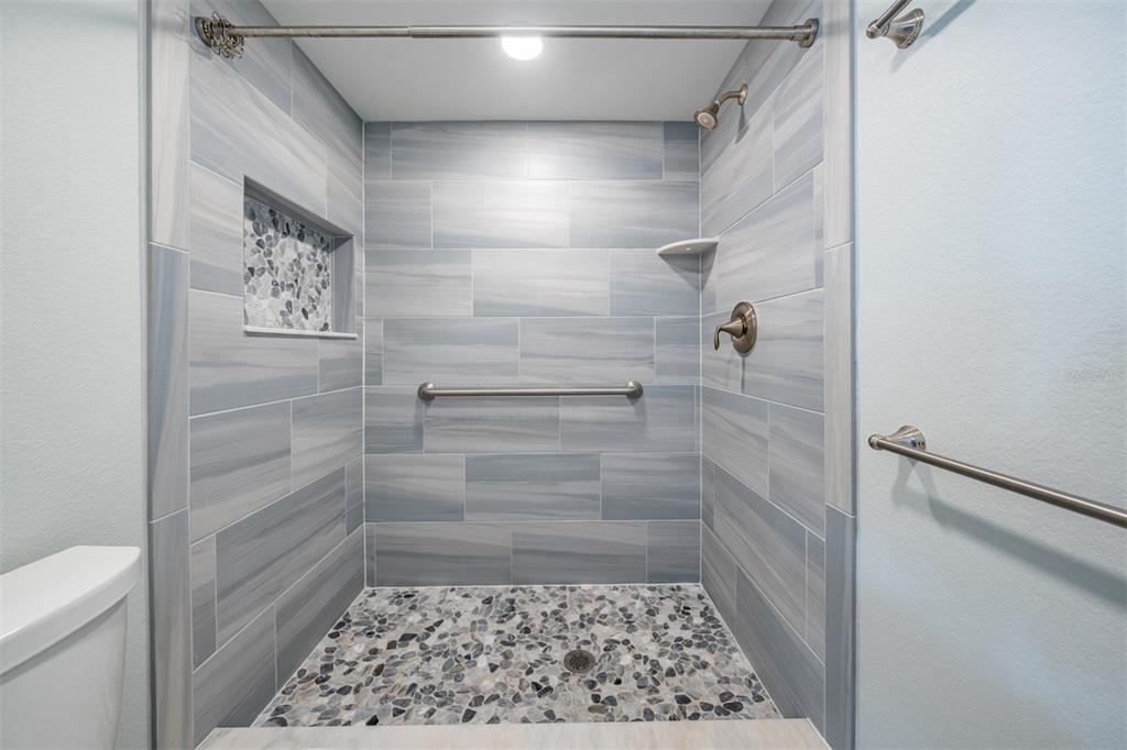 9 Haig Place, Unit 104 Dunedin, FL 34698 - Photo 13 of 59 a bathroom with a glass door shower