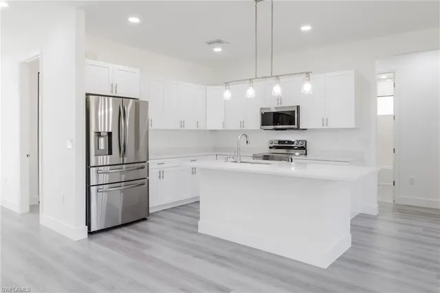 a kitchen with stainless steel appliances granite countertop a refrigerator a stove a sink and a microwave