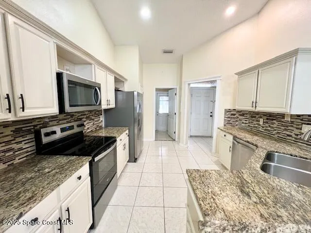 a kitchen with stainless steel appliances granite countertop a stove refrigerator and microwave