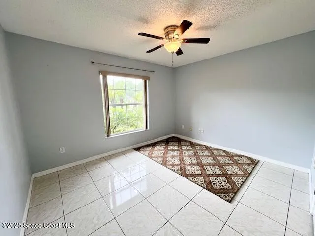 an empty room with windows and ceiling fan