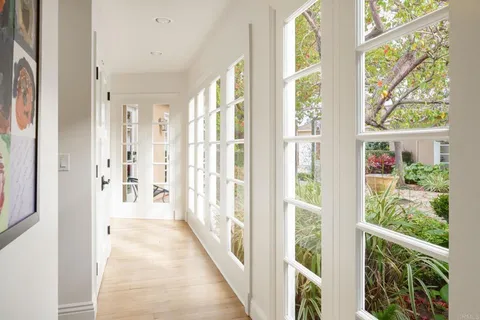 a view of a hallway with wooden floor and windows