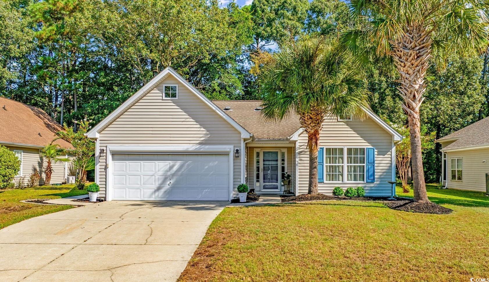 Traditional-style home featuring concrete driveway, a front lawn, and a garage