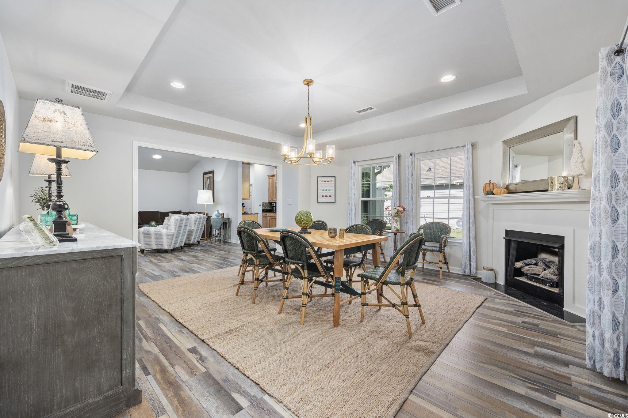 4618 Fringetree Drive Murrells Inlet, SC 29576 - Photo 11 of 40 Dining area featuring a raised ceiling, light wood-type flooring, a fireplace with flush hearth, recessed lighting, and a chandelier