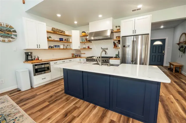 a kitchen with stainless steel appliances a sink a stove a refrigerator and cabinets