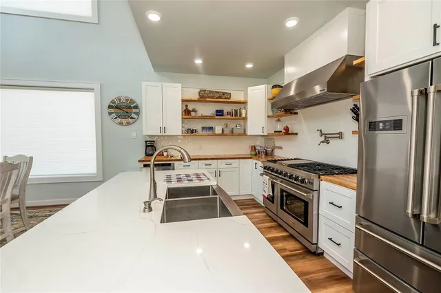 a large kitchen with stainless steel appliances granite countertop a stove oven and a refrigerator
