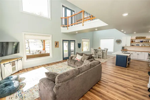 a living room with couches and a dining table with wooden floor