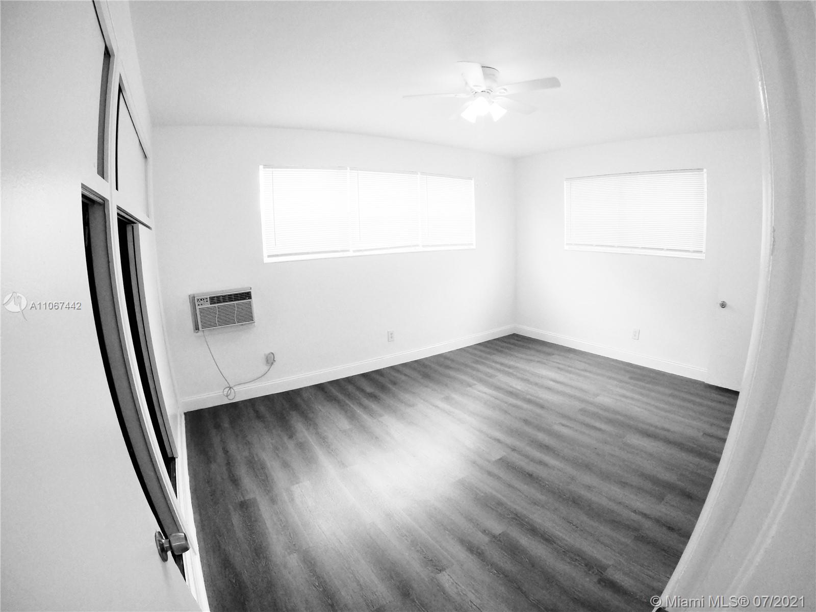 809 85th Street Miami Beach, FL 33141 - Photo 21 of 32 an empty room with wooden floor and windows