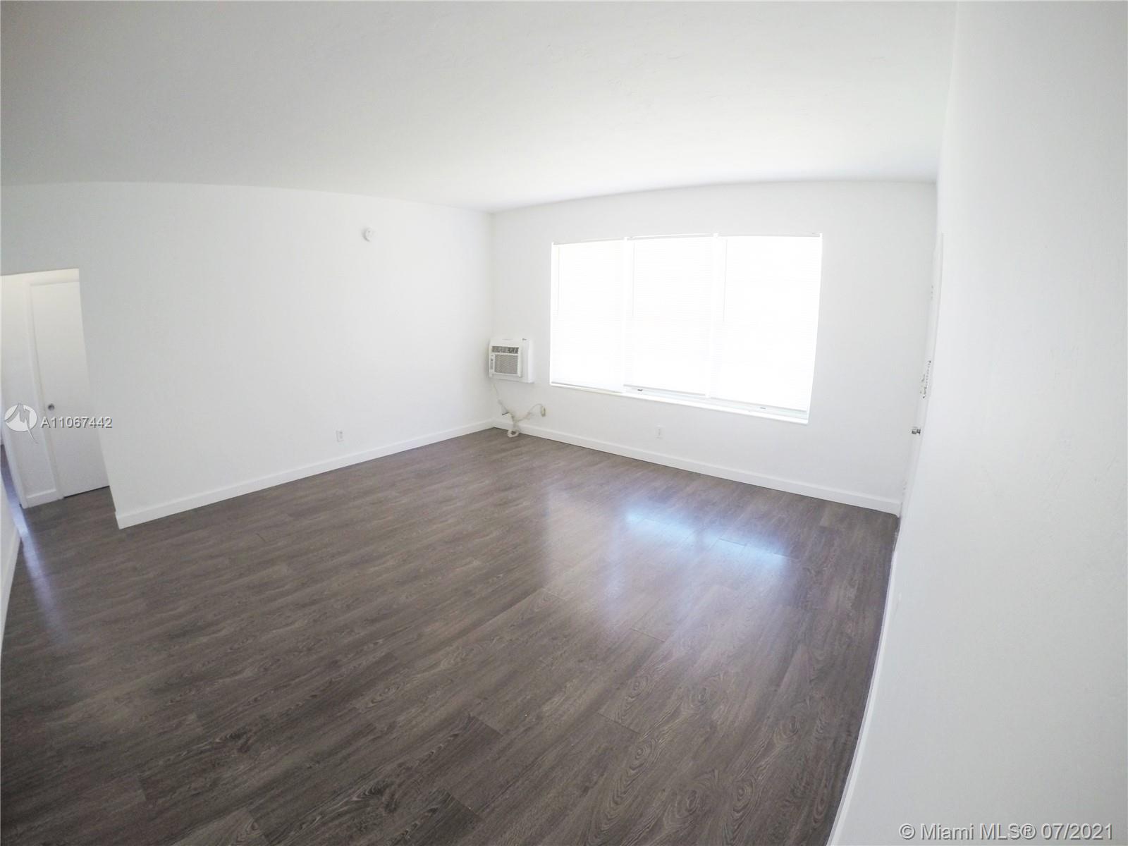 809 85th Street Miami Beach, FL 33141 - Photo 7 of 32 an empty room with wooden floor and windows