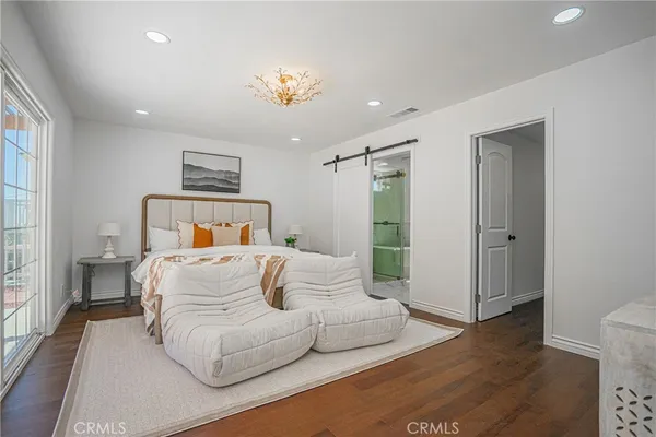 a bedroom with a large bed and wooden floor