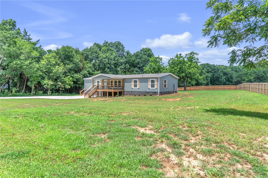 108 Old River Road Iva, SC 29655 - Photo 2 of 31 A welcoming home with a covered front porch, set against a backdrop of mature trees and open green space.