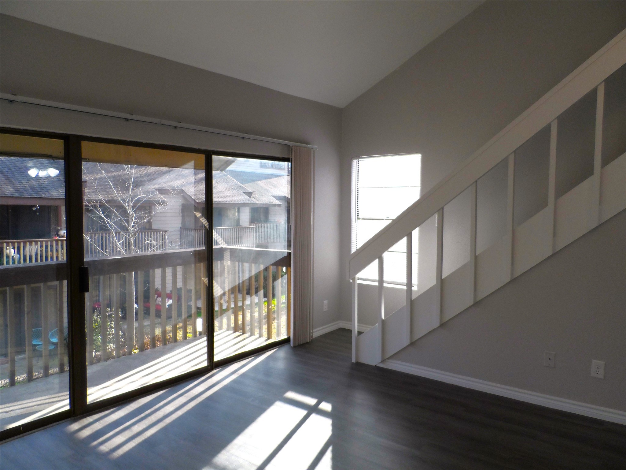 12900 Walden Road, Unit 618F Montgomery, TX 77356 - Photo 2 of 12 Bright and open living area featuring wood-look flooring, vaulted ceiling, and sliding glass doors leading to the private balcony.