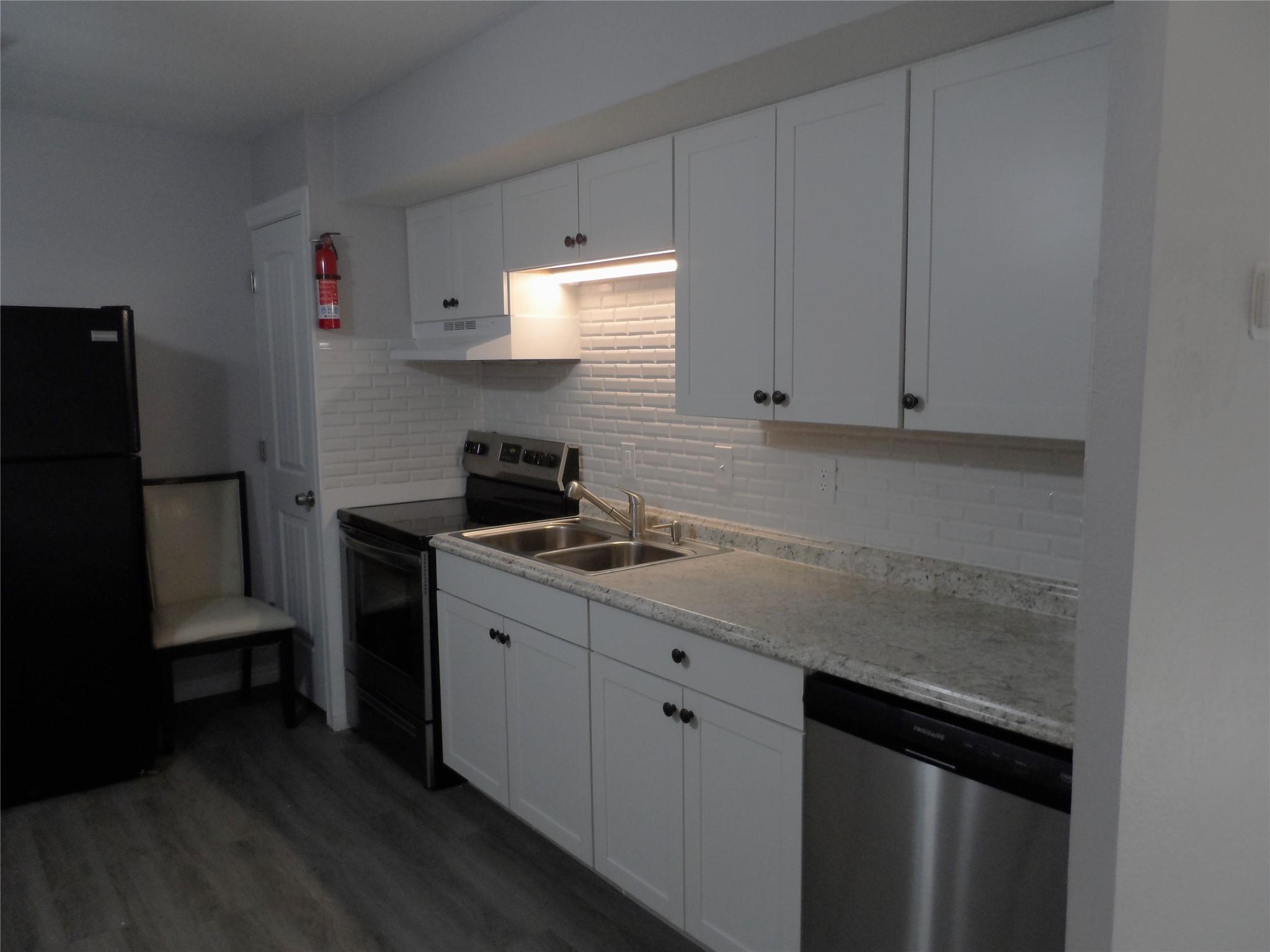 12900 Walden Road, Unit 618F Montgomery, TX 77356 - Photo 5 of 12 Updated kitchen featuring white cabinetry, granite countertops, stainless steel appliances, and modern subway tile backsplash.
