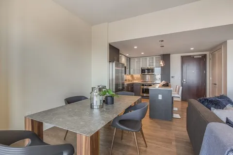 a kitchen with stainless steel appliances kitchen island granite countertop a table chairs and a refrigerator