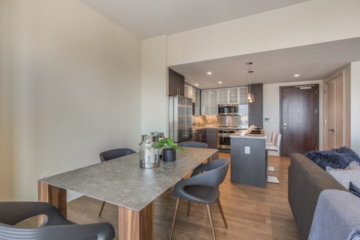 a kitchen with stainless steel appliances kitchen island granite countertop a table chairs and a refrigerator