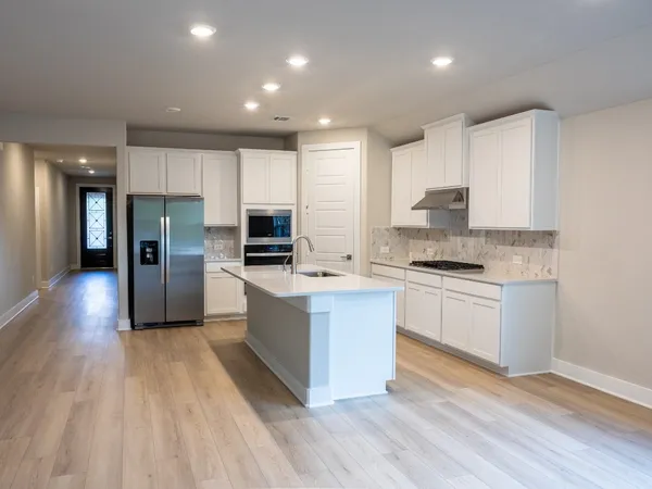 a large kitchen with stainless steel appliances kitchen island granite countertop a large counter top and wooden floors